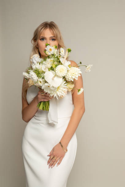 istock Vertical confident charming romantic blond female bride in white elegant dress covered by bouquet of white field flowers 1444149768