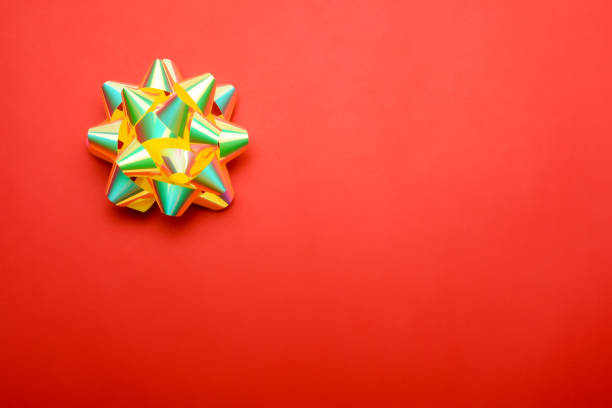 A person is holding a vibrant orange and white bow delicately in their hand, showcasing the intricate detail of its design and craftsmanship
