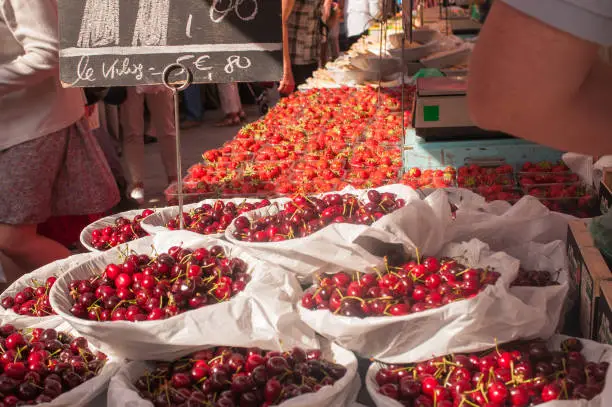 Photo of Market stall brimming with bowls of red ripe cherries