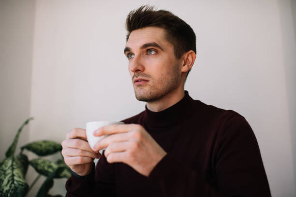 istock Pensive brunet man holding porcelain mug with hot tea and thinking about ideas during weekend in home apartment, contemplative male with hot caffeine beverage feeling pondering in cafeteria interior 1444171198