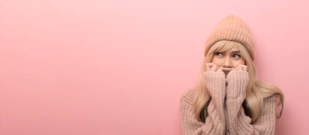 Portrait of Caucasian young woman wearing sweater over pink background stock photo