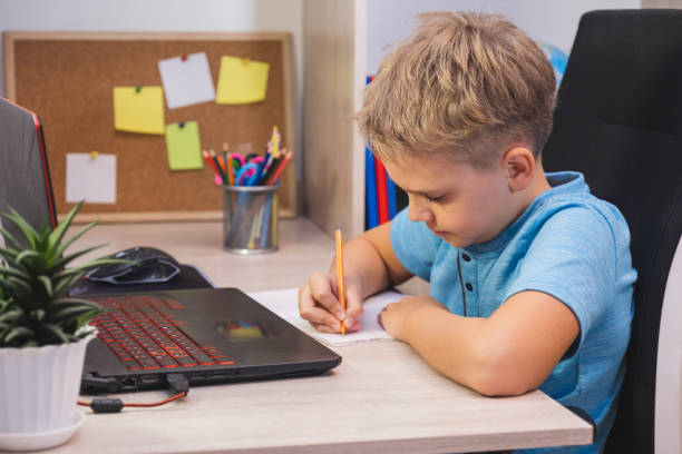 istock Distance learning, online education. A schoolboy studies at home with laptop and does school homework. 1444182210