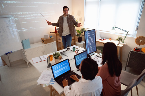 Coding class. Teacher giving computer science lecture, projecting slideshow with programming code.