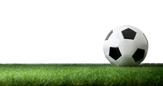 Front view of classic soccer ball on artificial grass and white isolated background. Horizontal panoramic composition.