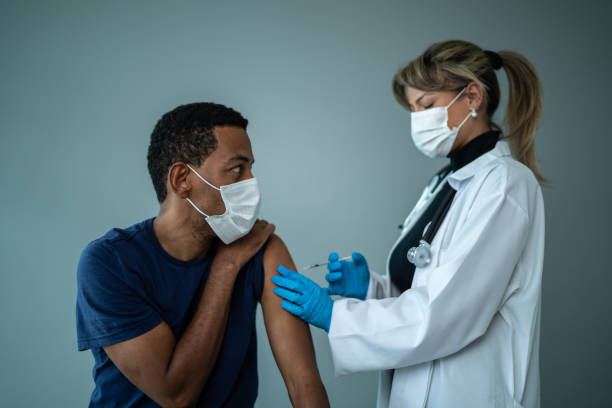 istock Doctor vaccinating a mature man - wearing a protective face mask on a studio shot 1444185272