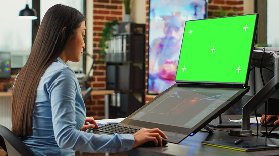 Female office worker using game developing interface and greenscreen display on monitors. Artistic editor working with blank chroma key template on isolated copyspace, planning 3d project.
