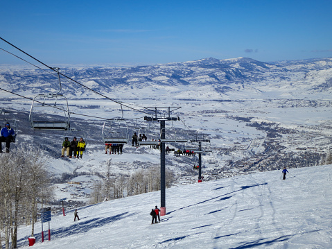 Steamboat Springs, Colorado, USA-February 1, 2013:  Chairs filled with people on the Four Points Lift, Steamboat ski resort, Colorado. Steamboat Springs in the valley below.