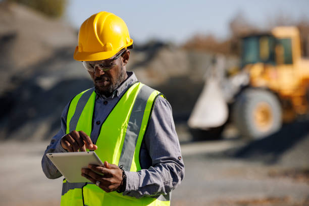 porträt eines ingenieurs mit schutzhelm mit digitalem tablet bei der arbeit auf der baustelle - building activity construction manual worker men stock-fotos und bilder