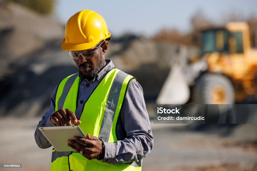 Portrait of male engineer with hardhat using digital tablet while working at construction site Construction Site Stock Photo
