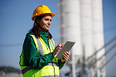 Portrait of female engineer with hardhat using digital tablet while working on her work site