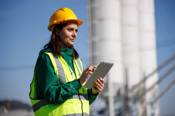 portrait of female engineer with hardhat using digital tablet while working on her work site - mining engineer oil industry construction site imagens e fotografias de stock
