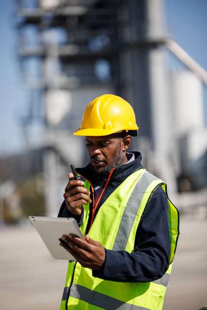 Portrait of industry worker or engineer using walkie-talkie and digital tablet at industrial facility stock photo