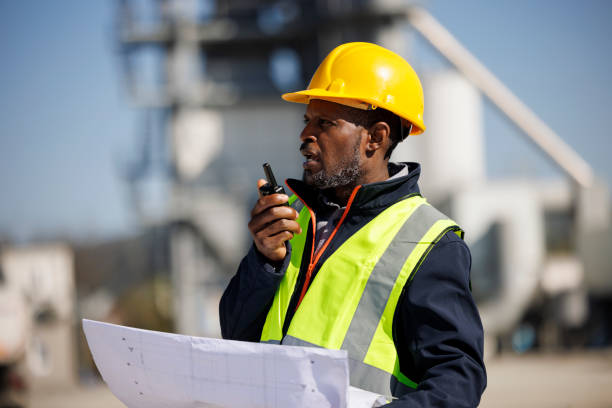 portrait of industry worker or engineer holding blueprint and using walkie-talkie at industrial facility - mining engineer oil industry construction site imagens e fotografias de stock