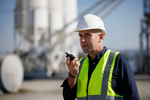 Portrait of an engineer using walkie-talkie at industrial facility