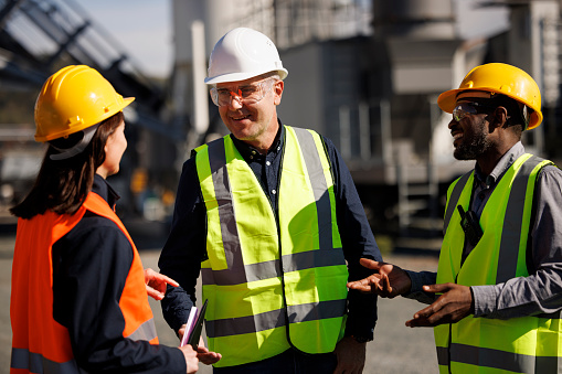 Three multi-ethnic engineers chatting at industrial facility