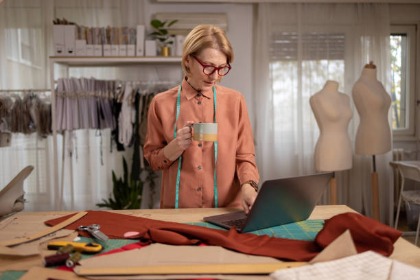 istock Fashion designer enjoying a cup of coffee while using a laptop 1444193558