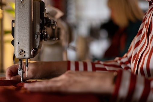 Close-up of the hands of an unrecognizable person using a sewing machine and making new clothes