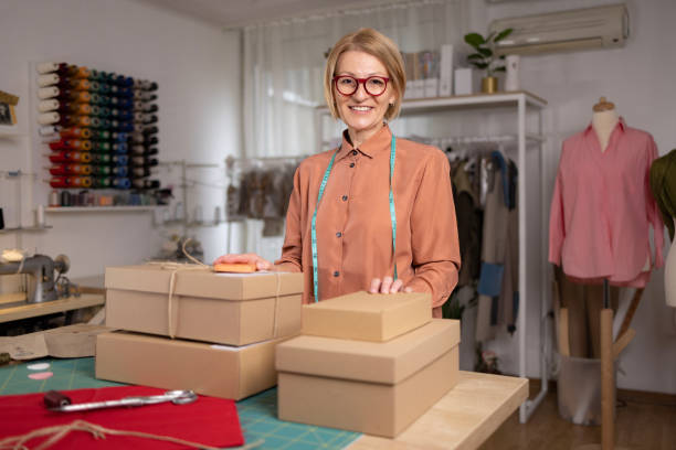 istock Middle aged female clothes designer readying the packages for shipment. Looking at camera 1444194401