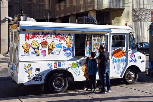Toronto, Canada - August 11, 2022: Family waits for treats at a Master Soft and Delight ice cream treat truck on Queen Street in front of Nathan Phillips Square.