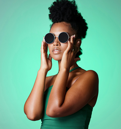 Fashion, black woman and glasses with a model with a vintage or retro sunglasses or eyewear in studio on a green background. Trendy, style and confident with a young african american female with afro