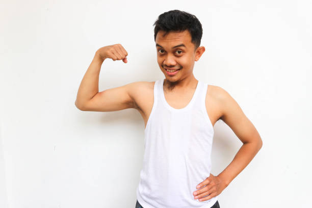 Happy slim man wearing undershirt, looking at camera showing biceps