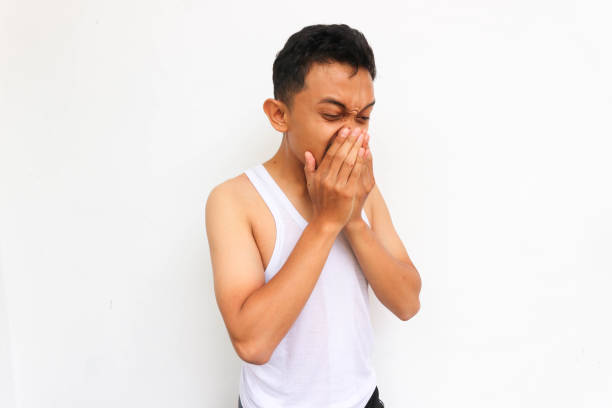istock Man sneezing. Funny young guy sneezing wearing white undershirt on white background 1444199386
