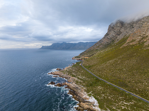 Elevated view mountain along coastline with road ocean and cloudy sky