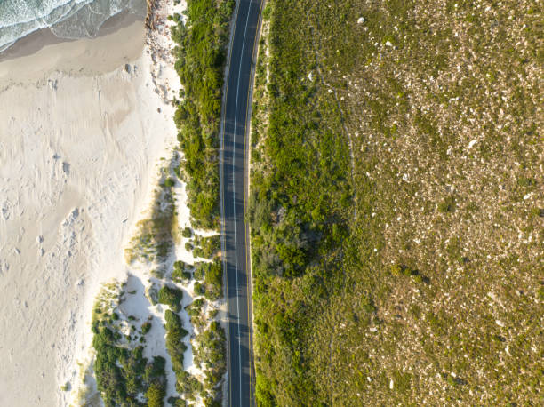 istock Overhead view coastal road with green mountainside and sandy beach 1444199783