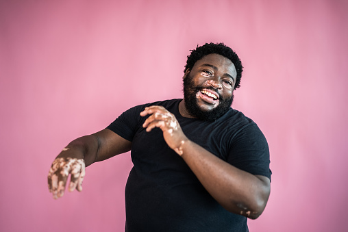 Portrait of a mid adult man dancing on a pink background