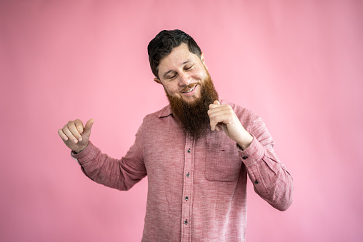 Mid adult man dancing on a pink background