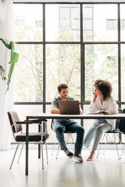 istock Young multiracial couple working at home. Bright spacious loft apartment with big window. 1444204402