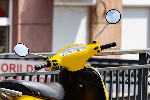 Close up to a motorcycle scooter or moped yellow handlebar with gauge and round mirrors