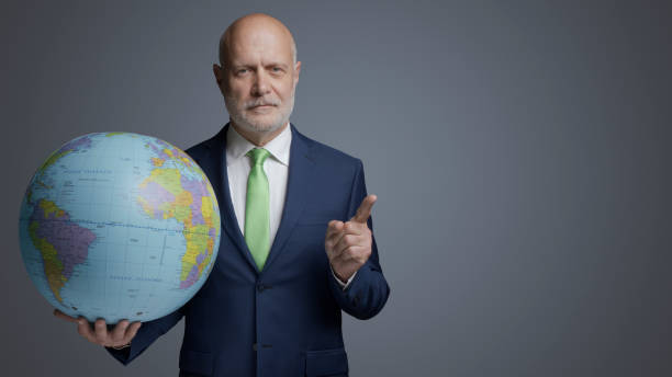 istock Businessman holding a globe and pointing 1444210726