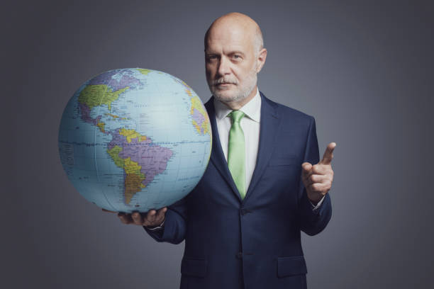 istock Businessman holding a globe and pointing 1444211498
