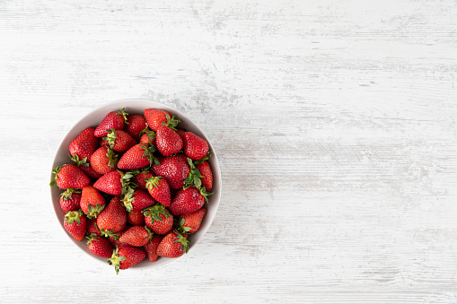 Fresh strawberries on white wooden table background