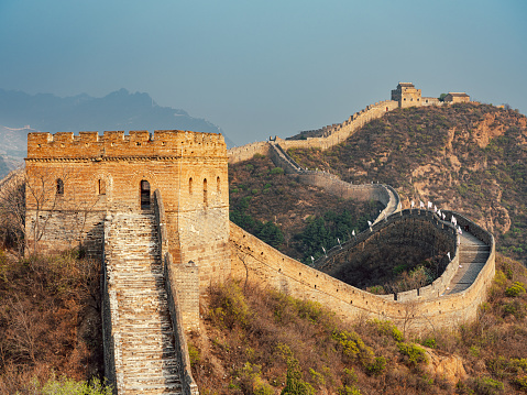 A high angle closeup shot of the famous Great Wall of China surrounded by green trees in summer