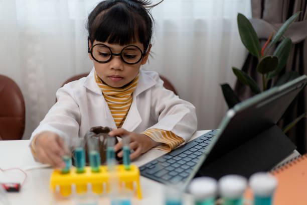 petite fille asiatique mesurant la température de l’eau chaude et froide pour un cours expérimental en ligne scientifique facile - computer lab child internet development photos et images de collection