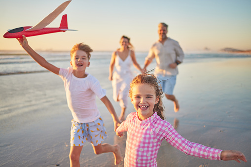 Freedom, happy family and beach with happy children running and playing with parents. Travel, wellness and energy with excited kids bonding and having fun, laugh on fun activity with mom and dad