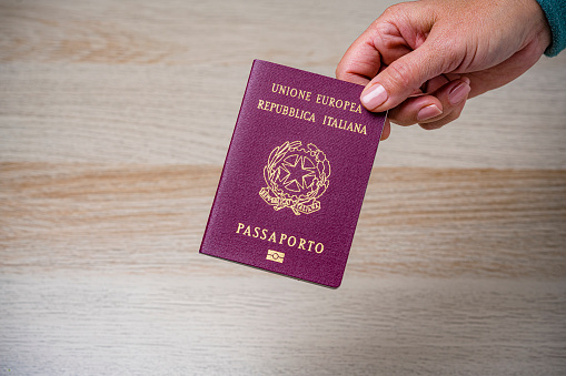 Close up view of woman's hand holding italian passport. High resolution 42Mp studio digital capture taken with Sony A7rII and Sony FE 90mm f2.8 macro G OSS lens