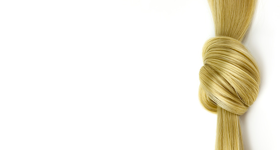 Blonde hair lock tied in knot. Lock of blonde wavy hair on white background, top view