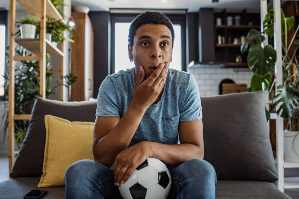 istock Focused black man supporting his favorite team at home 1444221923