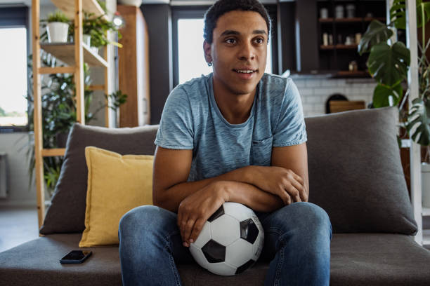 istock Young man watching a soccer game at home 1444222264