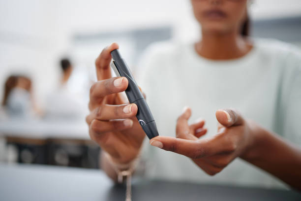 diabetes, finger and black woman with blood sugar test on to check levels of student while sitting at desk. healthcare, health and female prick to use glucose meter for insulin and wellness - close up medical test exam people imagens e fotografias de stock