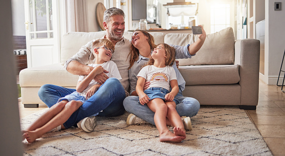 Happy, relax and selfie with family in living room for love, media and support together. Smile, support and and internet with parents and children posing for phone camera at home for social media