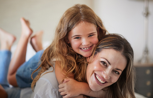 Relax, hug and portrait of mother with child in New Zealand family home enjoy bonding together. Care, love and happy mother smiling with young daughter in house on weekend for leisure time.