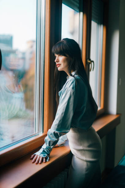 istock Woman daydreaming and looking through the window 1444238939