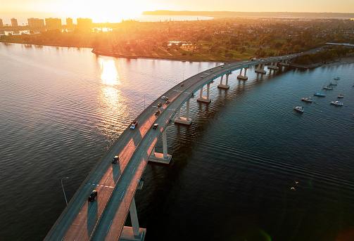 Coronado Bridge in San Diego California during golden hour with cars crossing the bridge and boats in San Diego Bay