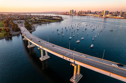 Coronado Bridge in San Diego California during golden hour with cars crossing the bridge and boats in San Diego Bay. United States of America famous city skyline