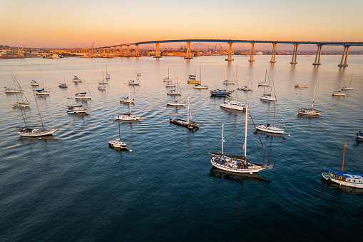Empty sailboats in front of Coronado Bridge in San Diego bay during golden hour. California coast at sunset