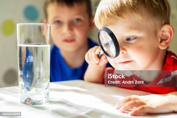 The Child Boy Looking At Water In A Glass Through Magnifying Glass Stock Photo - Download Image Now